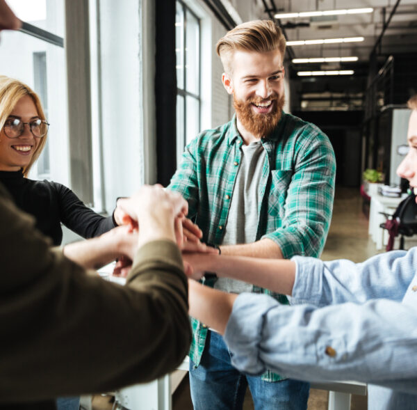 Image of young colleagues in office holding hands of each other. Looking aside.